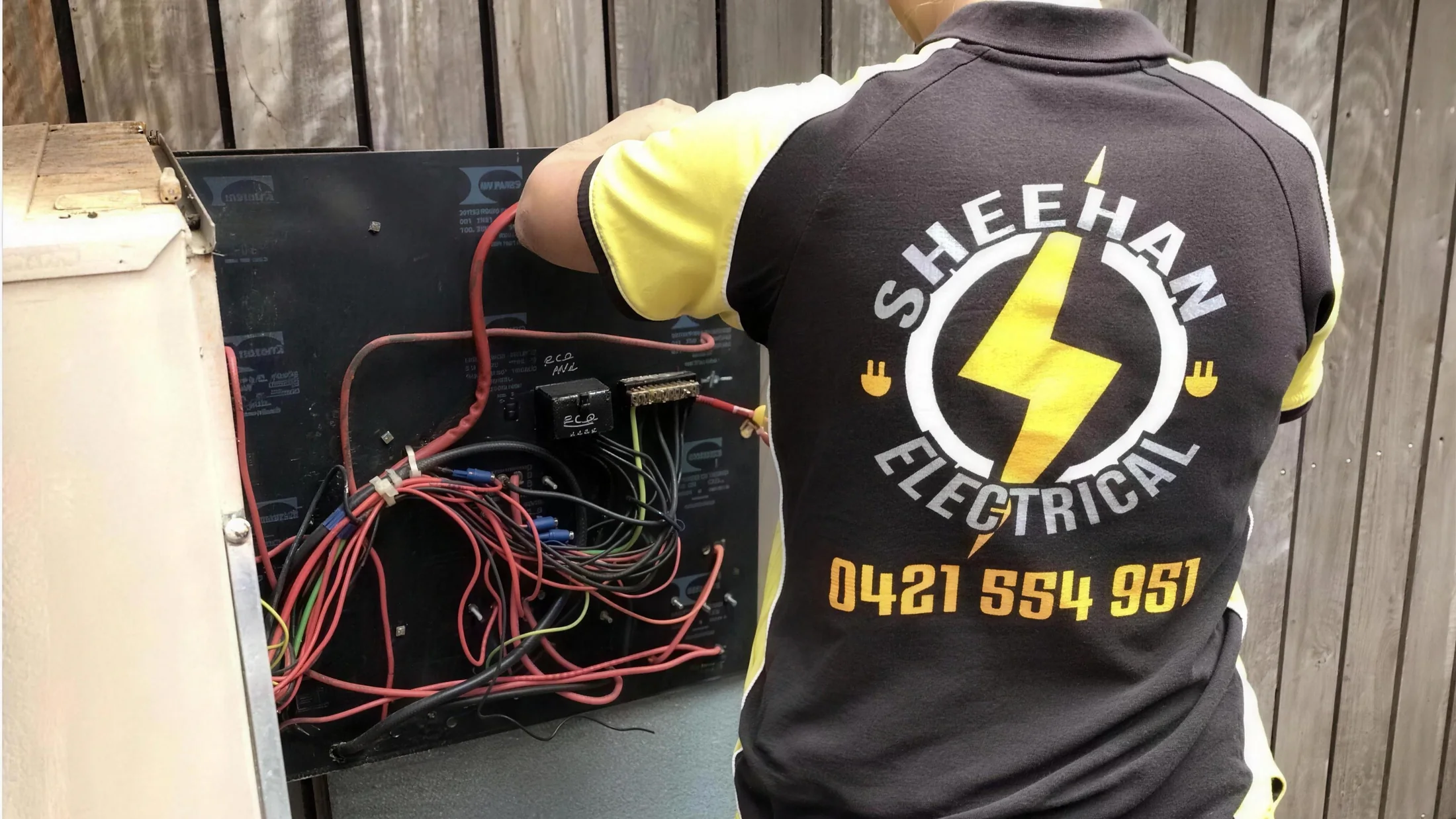 A Sheehan Electrical tradesperson working on an open switchboard
